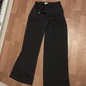 Svarta vida kostymbyxor från Hm - Snygga svarta kostymbyxor från Hm med vida ben. Byxorna har dragkedja och knapp framtill samt diskreta fickor bak. Perfekta för en stilren look.