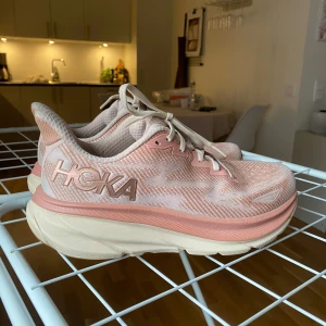 HOKA CLIFTON 9 - NYPRIS 1999:-  Endast använda några gånger sedan de inköptes i början på april 2025. Varit noga med att tvätta av dom efter användning. Säljes pga att de passar inte min fot  Storlek 41 1/3, Hoka är små på storleken så dessa passar mig som vanligtvis har strl 40 på skor.