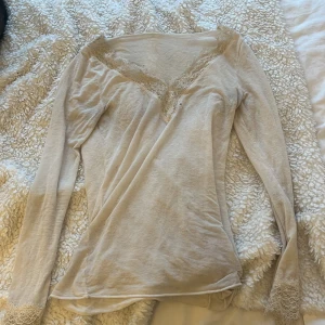 Beige långärmad topp med spetsdetaljer - Säljer denna vita insesemin (stava kanske fel) inte jätte bra skick eftersom den har hål i sig men funkar ändå!!!