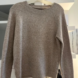 Beige stickad tröja från Vero Moda - Säljer en enkel och stilren beige stickad tröja från Vero Moda. Tröjan har rund halsringning, långa ärmar och ribbade muddar vid ärmslut och nederkant. Perfekt för lager-på-lager under kyliga dagar.