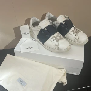 Valentino vita sneakers med svart detalj - Säljer ett par vita Valentino sneakers. Kommer med originalkartong och dustbag. Perfekta för dig som gillar stilrena och exklusiva sneakers.