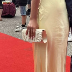 Apricot kuvertväska  - Säljer en elegant apricot kuvertväska med veckad och glittrig struktur. Använd vid ett tillfälle.🌞💛🌸