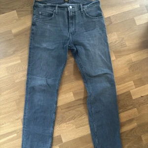 Grå jeansbyxor från Lee model Rider - Säljer ett par klassiska grå jeansbyxor från Lee model Rider. Byxorna har fem fickor, raka ben och normal passform. Perfekta för dig som gillar en tidlös stil och vill ha ett par jeans som funkar till det mesta.