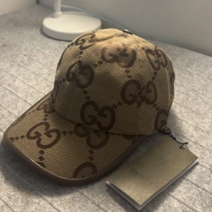 Beige gucci keps - Skriv dm för prisförslag eller video! Säljer en beige keps från Gucci med brunt GG-logomönster över hela kepsen. Kepsen har böjd skärm och bruna kanter. Märkeslapp och etikett medföljer. Perfekt accessoar för dig som gillar lyxiga detaljer. Storlek ”M”