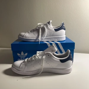 Adidas Stan Smith sneakers - Säljer dessa helt oanvända vita med blått Adidas Stan Smith skorna i storlek 40. Kommer med etikett och den originala skoboxen. Helt perfekta för vardagen. 💗
