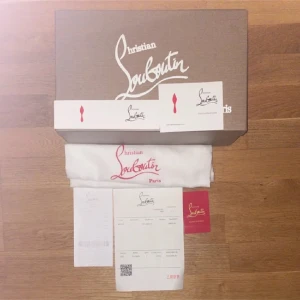 Christian Louboutin - Säljer ett par vita sneakers från Christian Louboutin med ikoniska röda sulor och coola nitar framtill. Skorna har snörning och är tillverkade i skinn. Kommer med originalkartong och dustbag. Skick 9-10 endast sulan som är smutsig, men enkelt att tvätta!!!