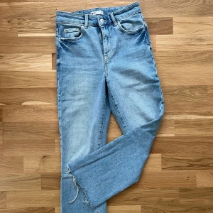 Ljusblå jeans från Ginatricot - Jeansen har hög midja, raka ben och råa, fransiga benslut för en avslappnad vibe. 