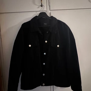 Svart manchesterjacka från Only - Säljer en svart manchesterjacka från Only med klassisk krage och silverfärgade knappar framtill. Jackan har två bröstfickor med lock och knappar samt långa ärmar. Perfekt för dig som gillar en tidlös och stilren look.