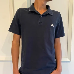 Burberry - Burberry pike, färg mörk blå, storlek M passar även S, skick 9.5/10. Ikoniskt Burberry-mönster syns på insidan av kragen. Personen på bilden är 175 cm. 