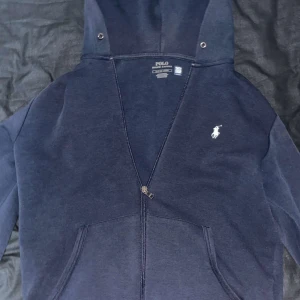 Mörkblå zip-hoodie från Polo Ralph Lauren - Mörkblå hoodie från Polo Ralph Lauren med dragkedja och vit broderad logga på bröstet.  Jag säljer nu denna kofta pga den inte kommit till någon användning. Tröjan är i väldigt bra skick . Pris kan diskuteras ❗️❗️❗️