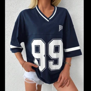 Oversized marinblå t-shirt med tryck - Snygg oversized t-shirt/ jersey i marinblått med vita detaljer och stort tryck med siffran 89 framtill. V-ringad hals med randig kant och breda ärmar med vit rand. 