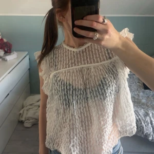 Vit spetsblus med volang - Söt blus i spets med spetsdetaljer. Från Nelly k storlek S. Säljs inte längre 