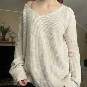 Beige oversized stickad tröja - Mysig beige stickad tröja från Knit-ted med djup v-ringning och lång ärm. Tröjan har en avslappnad passform och är perfekt för lager-på-lager. Ribbstickad struktur ger en stilren och mysig look.