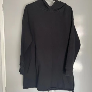Svart lång hoodie från 157 XS/S - Säljer en svart hoodie från 157 i storlek XS/S. Lång modell med slits på ena sidan. Dragsko längs med och trådsläpp syns på bild.