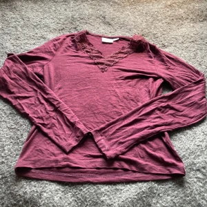 Vinröd långärmad topp från Gina Tricot - Säljer en vinröd långärmad topp från Gina Tricot med spetsdetaljer vid v-ringningen. Skönt material att ha på sig. Säljer pga för kort för mig. 