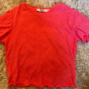 Säljer en snygg rosa topp från NA-KD. Den har korta ärmar och en fin volangdetalj vid nederkanten. Perfekt för en färgglad look!