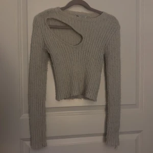 Vit ribbad tröja från Zara - Säljer en vit ribbad tröja från Zara med en unik cut-out detalj vid axeln. Tröjan har långa ärmar och är tillverkad i ett mjukt material som ger en skön känsla. Perfekt för att ge din outfit en trendig touch. Pris kan diskuteras 