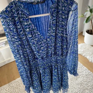 Blå mönstrad klänning från Zara - Säljer en blå mönstrad klänning från Zaramed v-ringning och långa ärmar. Lånade bilder!