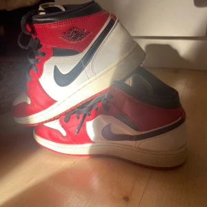 Nike Air Jordans i rött och vitt - ÄKTA Jordans mid. Säljer ett par klassiska Nike Air Jordans i rött, vitt och svart. Skorna har den ikoniska Nike-loggan på sidan och snörning framtill. Perfekta för dig som älskar sneakers med stil och komfort.