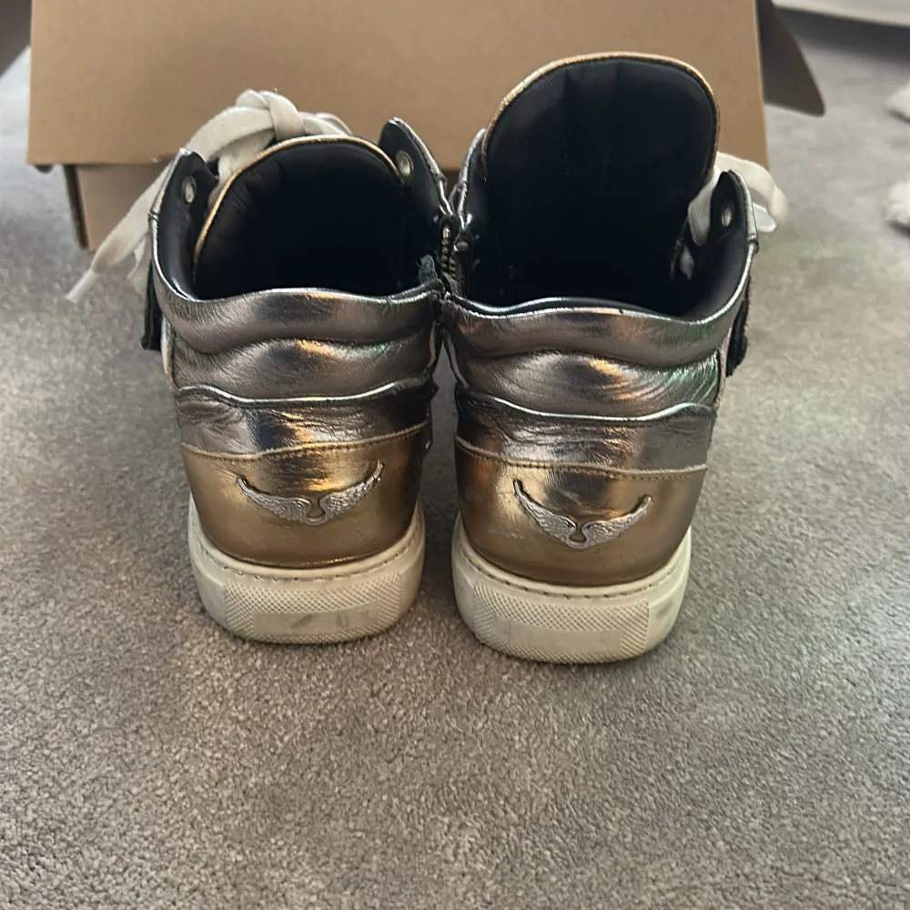 Snygga metallic sneakers från Zadig & Voltaire i silver och guld. Skorna har snörning och dragkedja på sidan för enkel på- och avtagning. Perfekta för att ge din outfit en cool touch. Box och dust bag kommer med, vill man ha fler bilder är det bara att fråga. Nypris 4000kr. Kengät.