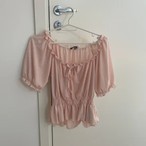 Rosa blus från Gina Tricot - Säljer en rosa blus från Gina Tricot med volangdetaljer och en söt rosett . Blusen har en elastisk midja som ger en fin passform. Blusen är perfekt för sommaren! Priset kan diskuteras💗