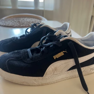 Svarta sneakers från Puma - Snygga svarta sneakers från Puma med vit sula och detaljer. Skorna har snörning och en bekväm innersula med SoftFoam för extra komfort. Perfekta för en avslappnad stil.