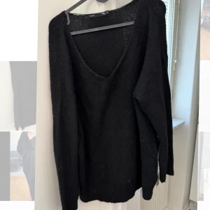 Svart stickad tröja från 157 - Säljer en svart stickad tröja från 157. Tröjan har en v-ringad hals och långa ärmar, perfekt för kyligare dagar. Den är mjuk och bekväm, idealisk för både vardag och avslappnade tillfällen.