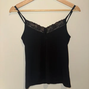 Svart linne med spetsdetaljer - Snyggt svart linne med smala axelband och spetsdetalj längs halsringningen❤️