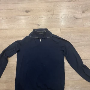 Mörkblå tröja med dragkedja - Säljer en stilren mörkblå tröja med dragkedja vid halsen. Tröjan har långa ärmar och en enkel design som passar perfekt för kyligare dagar. Perfekt för dig som gillar en klassisk look.