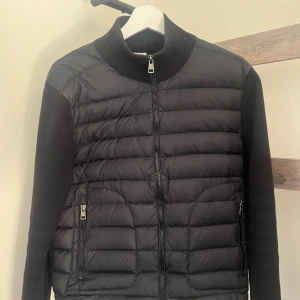 Moncler cardigan  - Hej! Säljer nu min stilrena Moncler cardigan i strl S. Den är använd några fåtal gånger vid speciellt golf. Cardiganen har ingen defekter eller små fel och funkar hur bra som helst nu till våren/sommarn. Den är köpt på NK i Stockholm och har alla äkthets verifieringar som helst. Kvittot är bortslarvat, men behövs det mer äkthets verifieringar, slå en pling bara. Jag skulle säga att den är lite liten i storleken och skulle nog passa perfekt om man är på väg mot storleken S.
