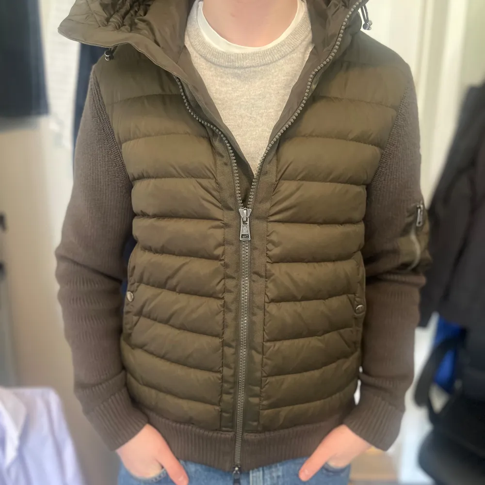 Säljer en snygg olivgrön jacka från Moncler med quiltad framsida och stickade ärmar. Jackan har en praktisk huva och dragkedja framtill. Storleken är Xl men passar L. Perfekt för kyligare dagar och nu till våren ! Köpt från Garmsmarket vilket garanterar att den är äkta! Hör av er ifall ni har några frågor . Takit.