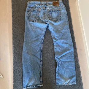 True religion jeans - Snygga true religion jeans som jag inte använder längre. De är i bra skick förutom hålen som syns på bilderna. Mått: Hela längd: 110 cm Innerben: 82 cm  Midja: 47 cm Benöppning: 23 cm Mitt på lår: 29 cm