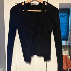 Svart ribbad tröja från MISSAY - Snygg svart ribbad tröja från MISSAY med en v-ringad design. Tröjan har långa ärmar och ett insytt linne. 