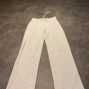 Grå mjukisbyxor med snörning - Säljer ett par bekväma grå mjukisbyxor med snörning i midjan. Byxorna har en loose passform och praktiska fickor framtill och baktill. Perfekta för en avslappnad stil. Har ett par likadana i storlek M också om någon är inte av dom😊💕