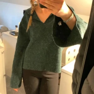Grön stickad tröja med krage - Säljer en mysig grön stickad tröja med krage och v-ringning. Tröjan har långa ärmar och en avslappnad passform, perfekt för kyligare dagar. Den är i storlek XS och passar bra till både jeans och leggings.