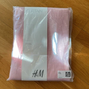 Rosa gardin från H&M - Säljer en fin rosa gardin från H&M. Gardinen mäter 250 cm x 100 cm och kommer i en förpackning. Perfekt för att ge ditt rum en mjuk och stilren känsla. 🌸