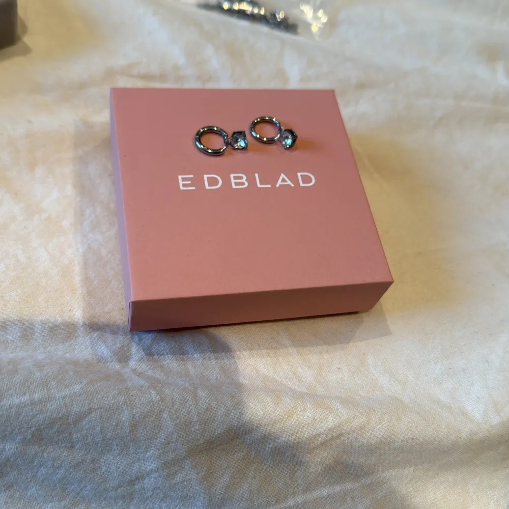 Snygga örhängen från Edblad med en elegant design. De har en rund form och är dekorerade med glittrande stenar som ger en lyxig känsla. Perfekta för att lägga till lite extra glamour till din outfit.. Asusteet.