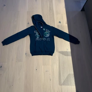 Mörkblå hoodie med drakkonst - Säljer en cool mörkblå hoodie med dragkedja och drakkonst på framsidan. Perfekt för en avslappnad stil. Den har långa ärmar och en bekväm huva.