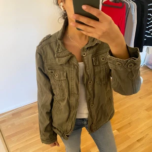 Trendig jacka med knappar - Säljer denna trendiga jackan som är perfket för sommaren, perfekt mörkgrön färg. Har inte kommit till användning, behövs även strykas 