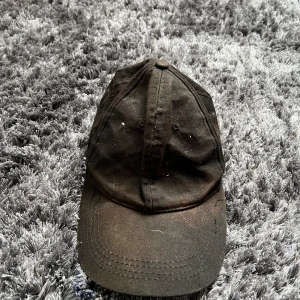 Svart keps - Säljer en svart keps med klassisk design. Kepsen har en böjd skärm och justerbar rem baktill för perfekt passform. Perfekt för vardagsbruk. Behövs rengöras. 
