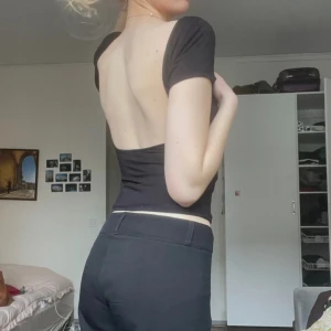 Svart topp med öppen rygg - Säljer en stilren svart topp med korta ärmar och en snygg öppen rygg. Toppen har en tight passform och är perfekt för en trendig look.