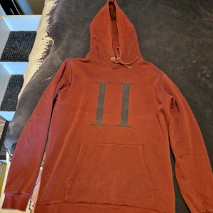 Grå hoodie från GANT - Säljer en stilren grå hoodie från GANT med ett tryck av deras logotyp och ett emblem på bröstet. Tröjan har en praktisk magficka och justerbar huva med snören. Perfekt för en avslappnad stil.