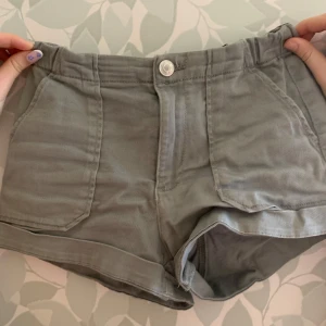 Gröna shorts från Kappahl - Snygga gröna shorts från Kappahl med praktiska fickor fram och bak. De har en knapp och dragkedja framtill för enkel påklädning. 