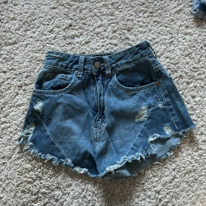 Blå jeansshorts från Costume - Snygga blå jeansshorts från Costume med slitna detaljer och fransig kant. 