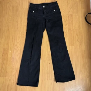 Svarta byxor med vida ben - Snygga svarta byxor med vida ben. Byxorna har knappar och dragkedja framtill samt fickor med knappar. Perfekta för en stilren look.