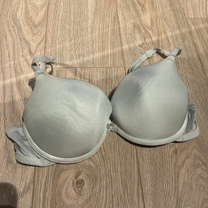 Grå bh med justerbara axelband - Säljer en stilren grå bh med justerbara axelband och slät yta. Perfekt för en bekväm och diskret look under kläderna.