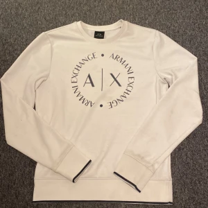 Vit tröja från Armani Exchange(billigare vid snabb affär) - Säljer en stilren vit tröja från Armani Exchange med deras logga tryckt på framsidan. Tröjan har långa ärmar och en rund halsringning. Perfekt för en avslappnad och trendig look.