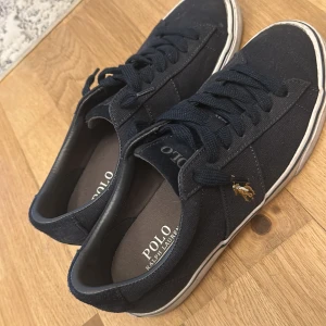 Svarta sneakers från Polo Ralph Lauren - Snygga svarta sneakers från Polo Ralph Lauren med klassisk design och snörning. Skorna har en diskret logga på sidan och är perfekta för en stilren look.