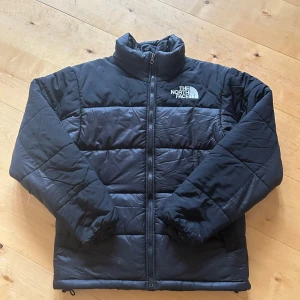 Svart pufferjacka från The North Face - Säljer en svart pufferjacka från The North Face. Jackan har en dragkedja framtill och är långärmad med en hög krage. Perfekt för kyliga dagar. 🖤