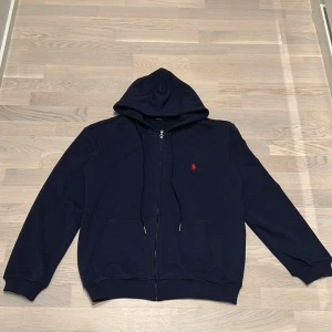Mörkblå hoodie från Ralph Lauren - Säljer en snygg mörkblå hoodie från Ralph Lauren med dragkedja och huva, knappt använd